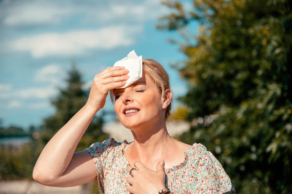 Blonde pretty Woman having hot flash and sweating on sun