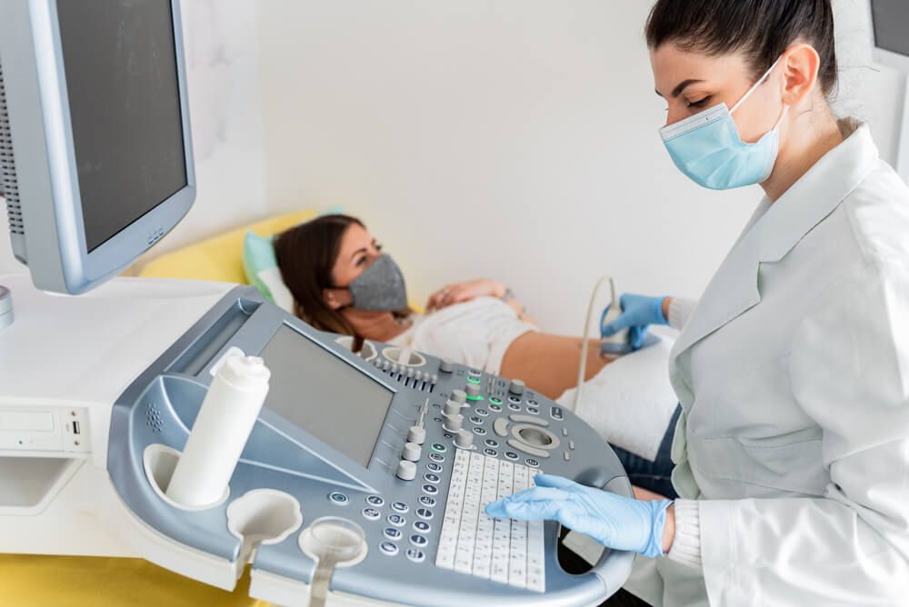 Gynecologist doctor wearing protection face mask does ultrasound