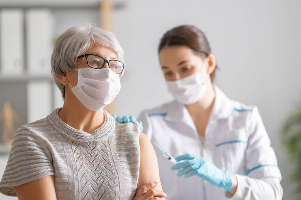 Doctor giving a senior woman a vaccination.