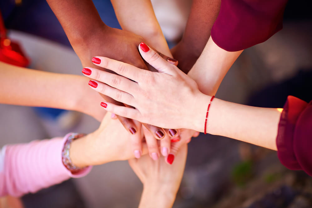 pile of female multiracial hands in union sign