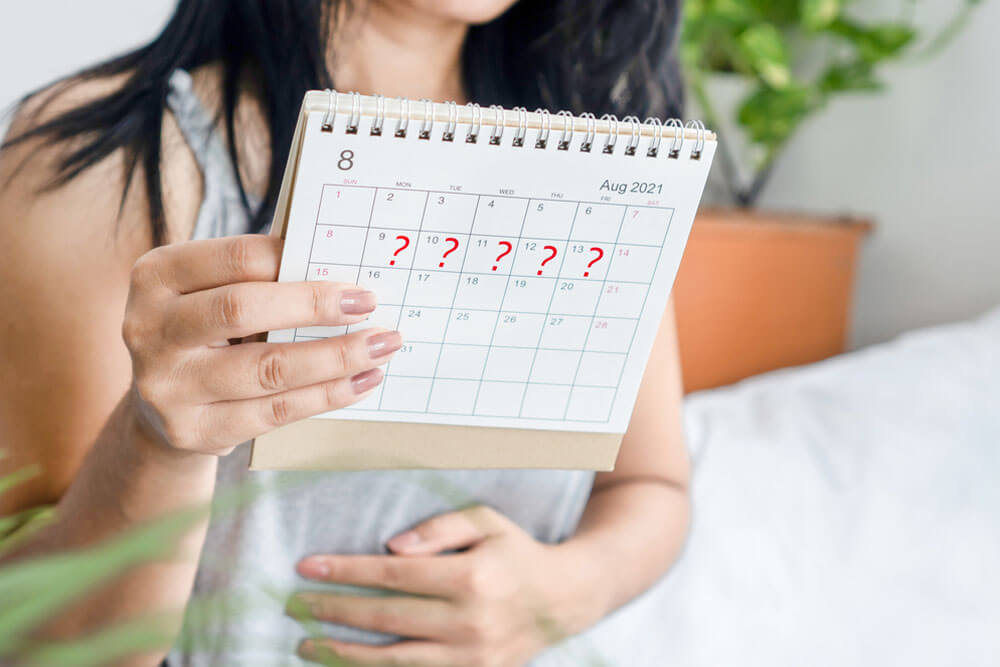 woman hand holding calendar with question mark waiting for late blood period