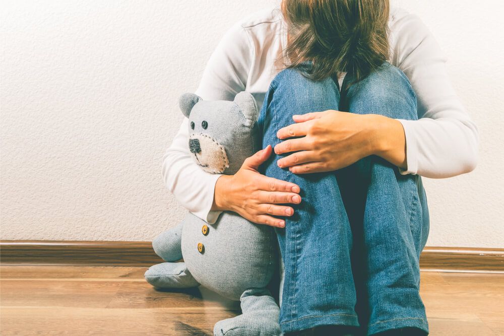 depressed woman holding teddy bear toy
