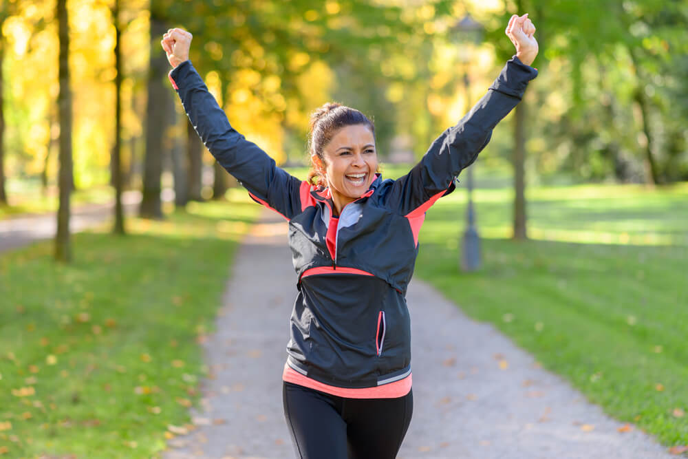 Happy fit middle aged woman cheering and celebrating as she walks