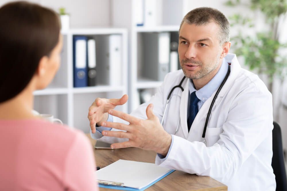 Experienced middle aged doctor talking to woman