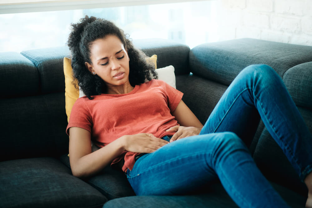 Young Black Woman With Menstrual Pain Lying On Sofa