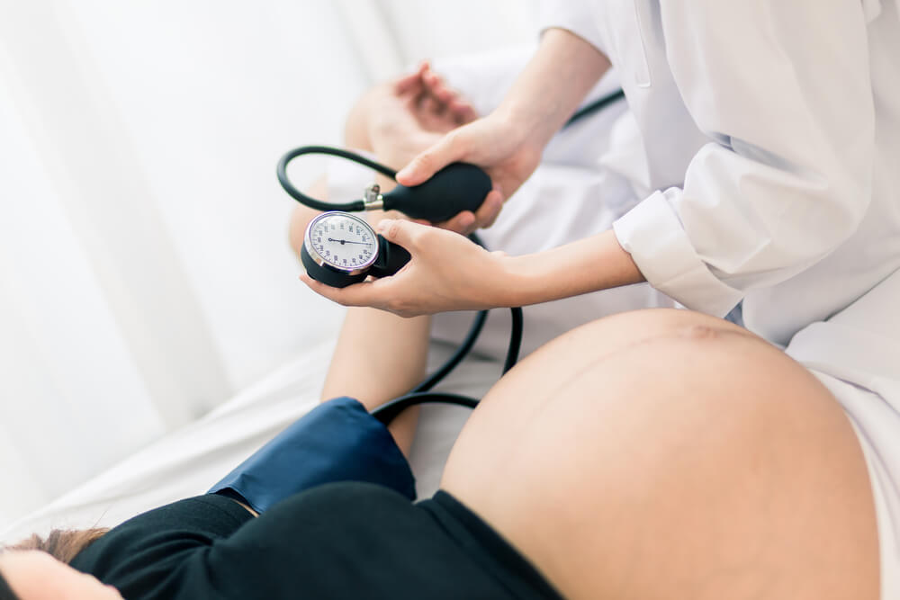 Female Obstetrician doctor measuring blood pressure of the pregnant woman