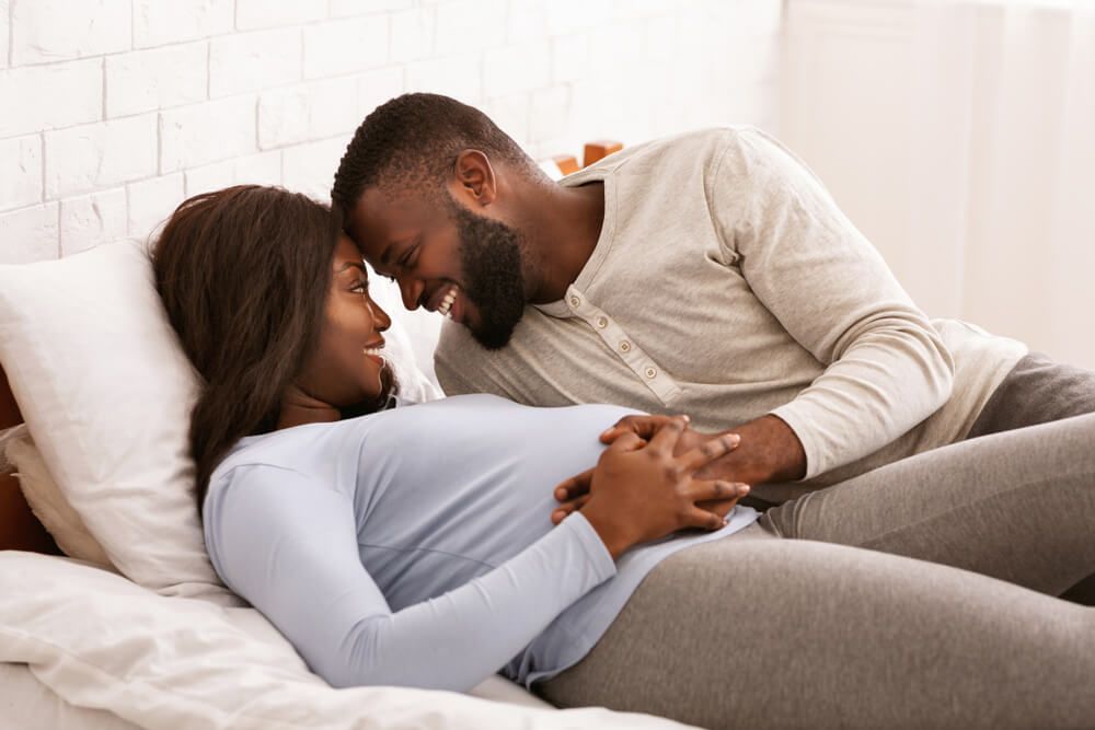 Pregnant couple in love cuddling in bed
