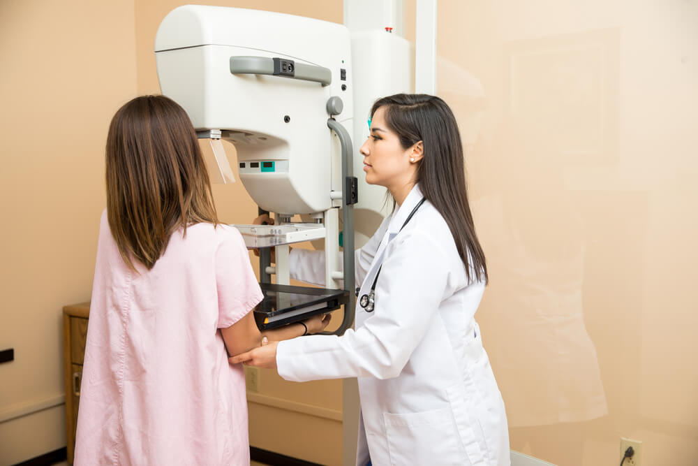 Pretty female doctor setting a patient in the correct position to get a mammogram in a clinic