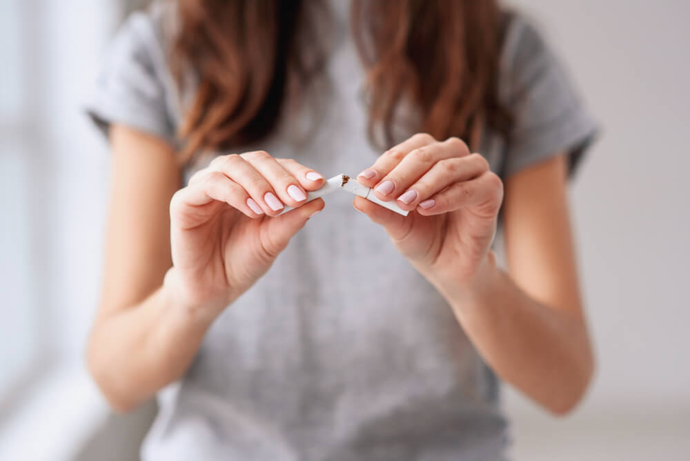 beautiful smiling girl holding broken cigarette in hands.