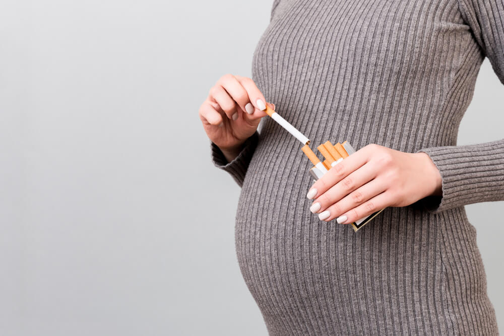 pregnant woman taking a cigarette from a pack