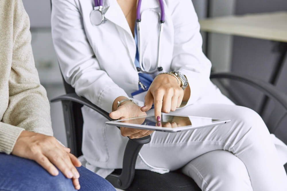 female doctor talking to a patient on a tablet