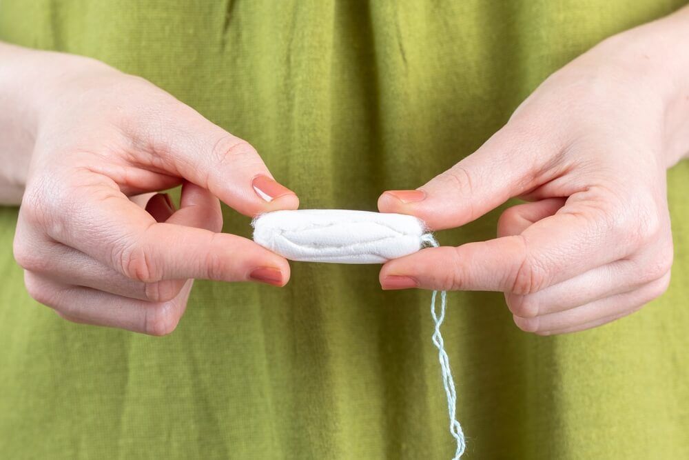 A woman holds a tampon in her hand.
