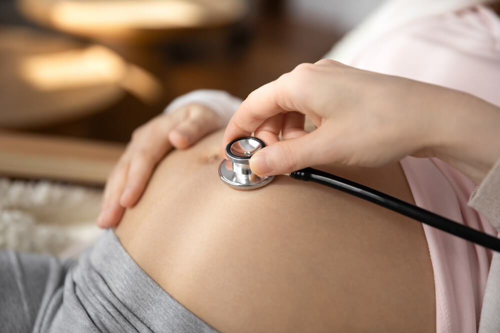 doctor hold stethoscope listen to pregnant woman baby bump