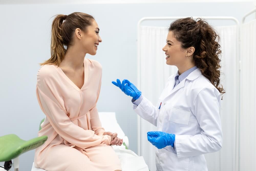 Gynecologist talking with young female patient during medical consultation in modern clinic