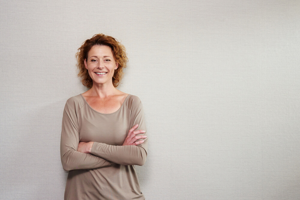 older woman smiling with arms crossed