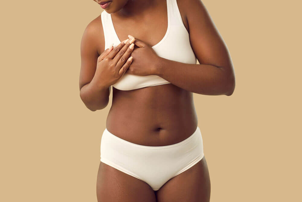 Beautiful plus size young black woman in underwear touches her chest when she feels strong pain