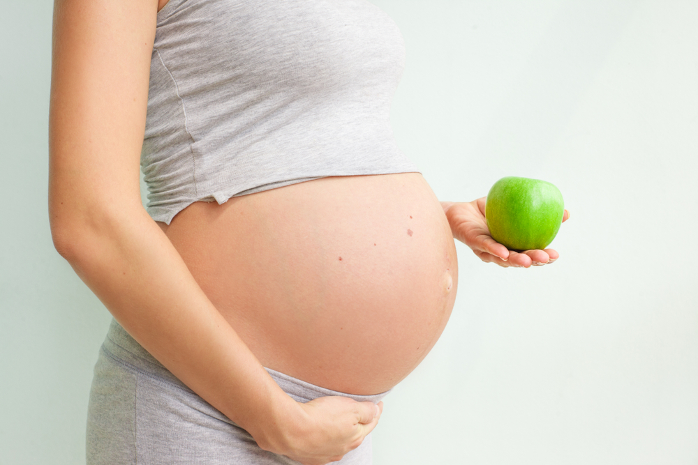 pregnant girl holding a green apple