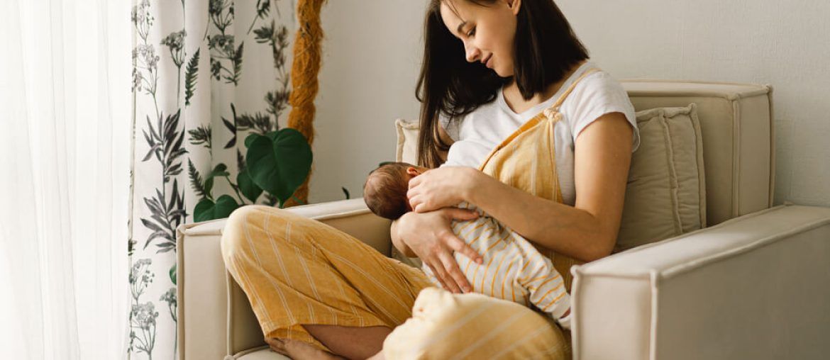 Newborn baby boy sucking milk from mothers breast.