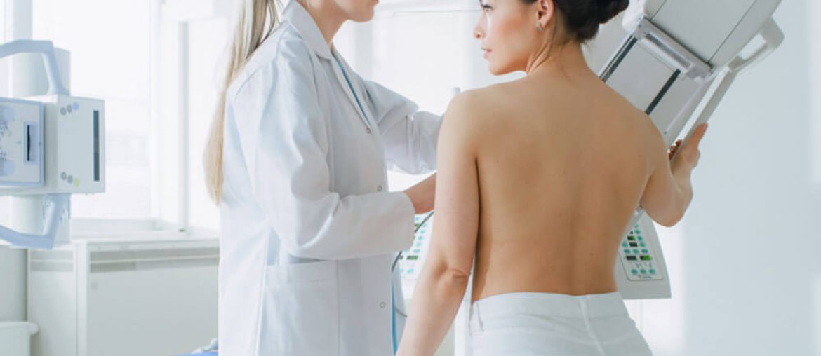 Doctor adjusts Mammogram Machine for a Female Patient.