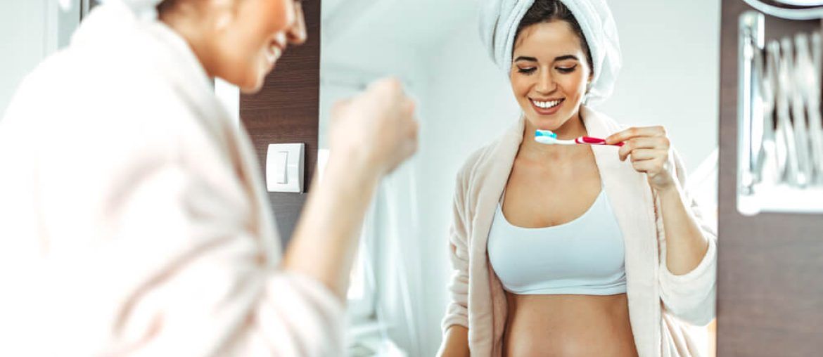 pregnant woman brushing her teeth in the bathroom