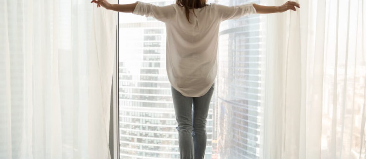 woman standing looking out of full-length window