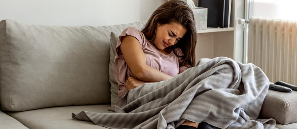 Unhappy woman holding hands on stomach suffering from abdominal pain