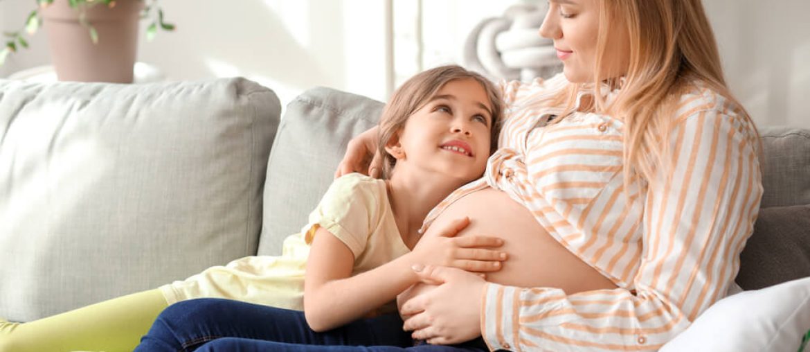 Beautiful pregnant woman with her little daughter at home