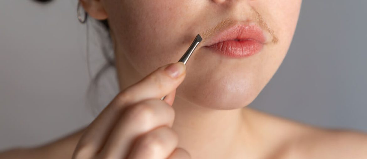 A young woman with a mustache tries to remove the hair over her lip