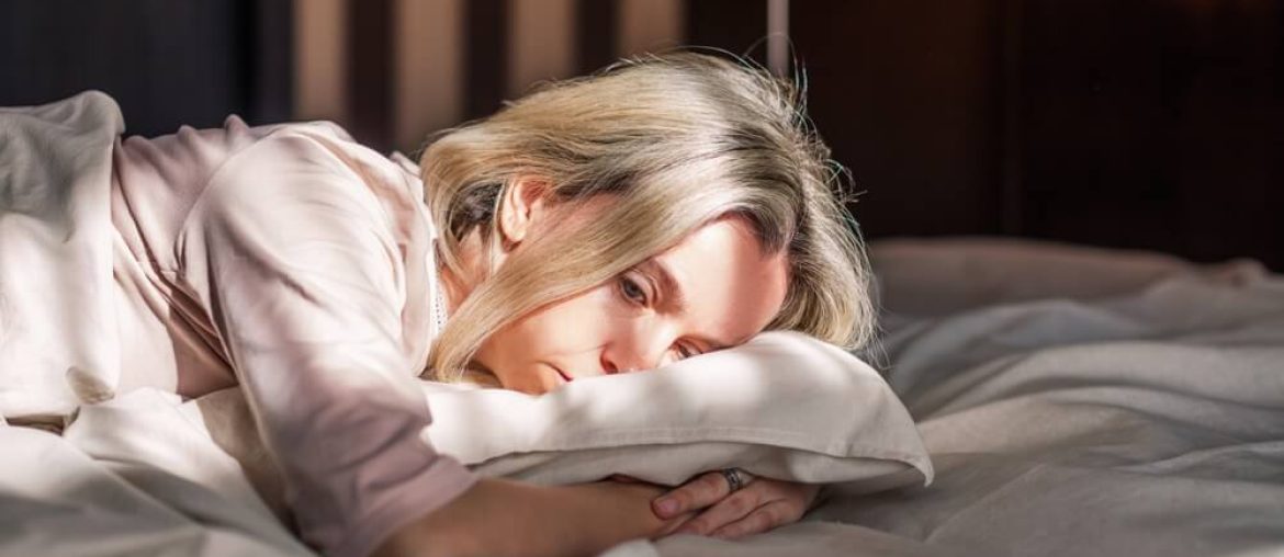 Tired middle aged woman lying in bed can't sleep late at morning with insomnia