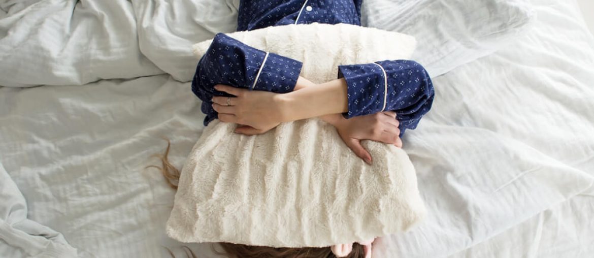 woman covers her face with a pillow