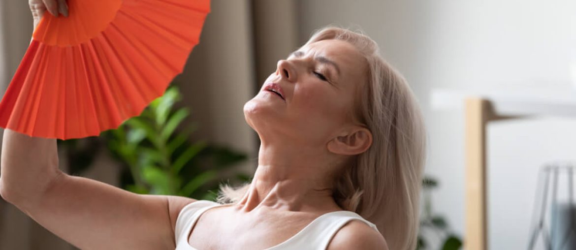 Exhausted older woman waving blue fan