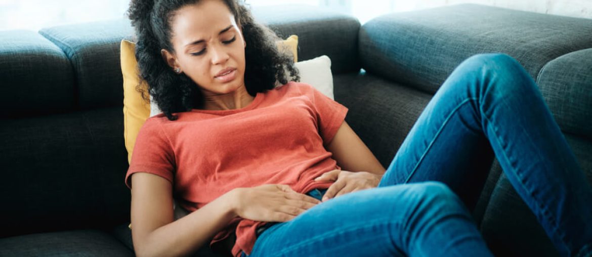 Young Black Woman With Menstrual Pain Lying On Sofa