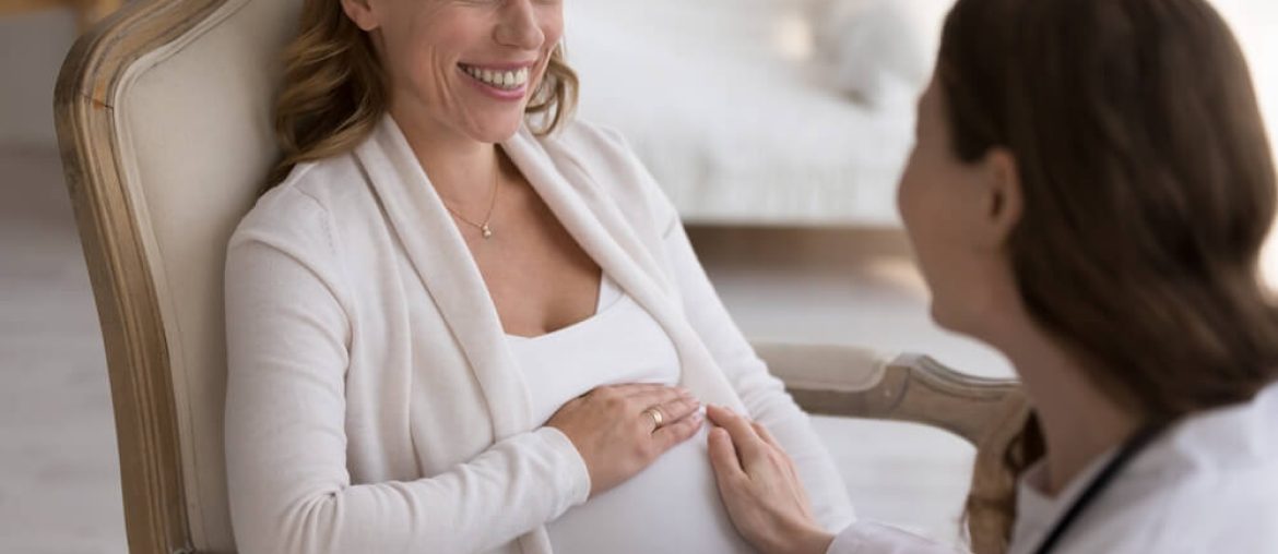 Obstetrician doctor visiting happy pregnant patient woman at home