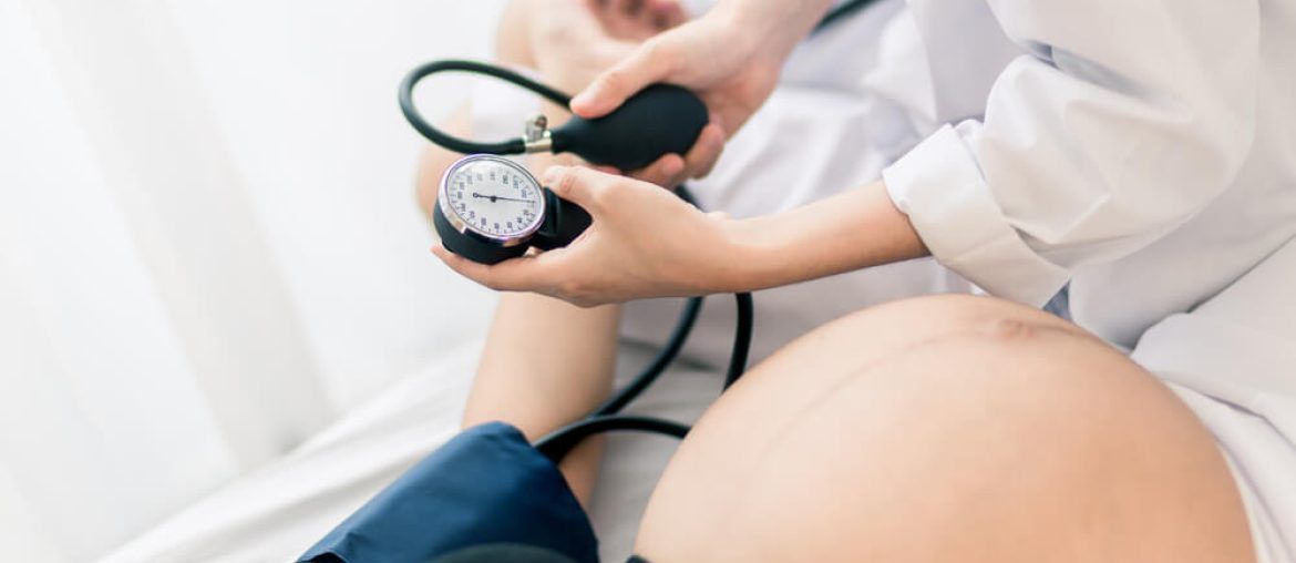 Female Obstetrician doctor measuring blood pressure of the pregnant woman