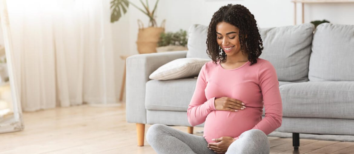 Beautiful happy pregnant woman hugging her tummy,