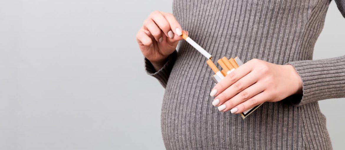 pregnant woman taking a cigarette from a pack