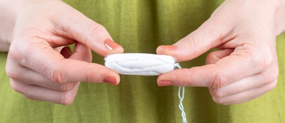 A woman holds a tampon in her hand.