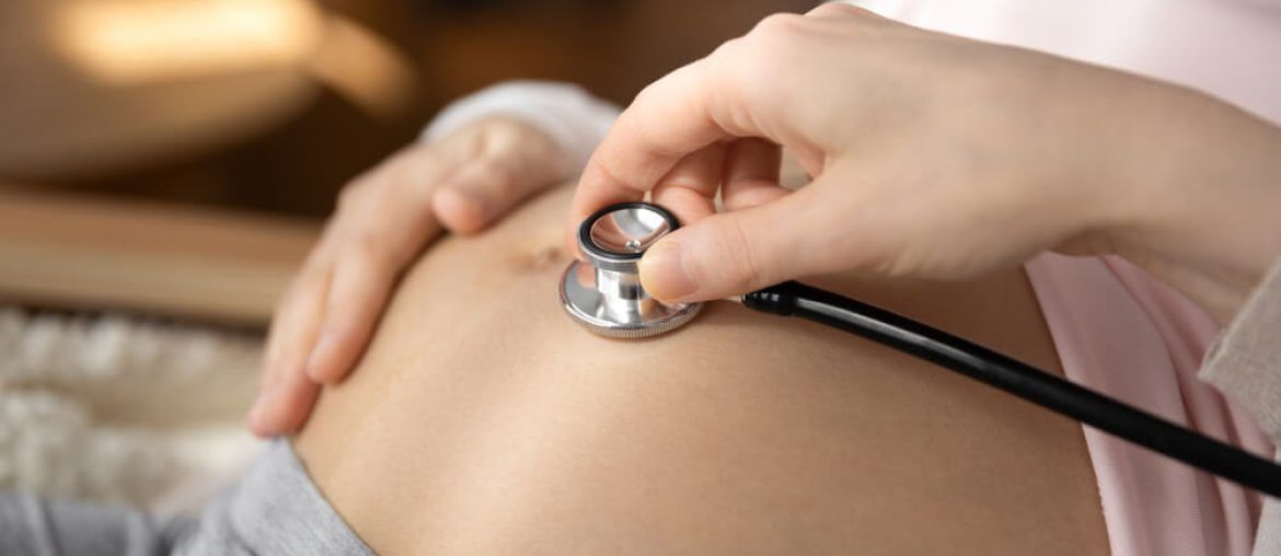 doctor hold stethoscope listen to pregnant woman baby bump