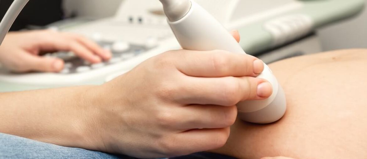 The hands of a doctor in close-up doing ultrasound to a pregnant woman