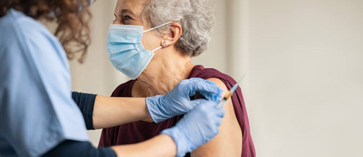 General practitioner vaccinating old patient in clinic