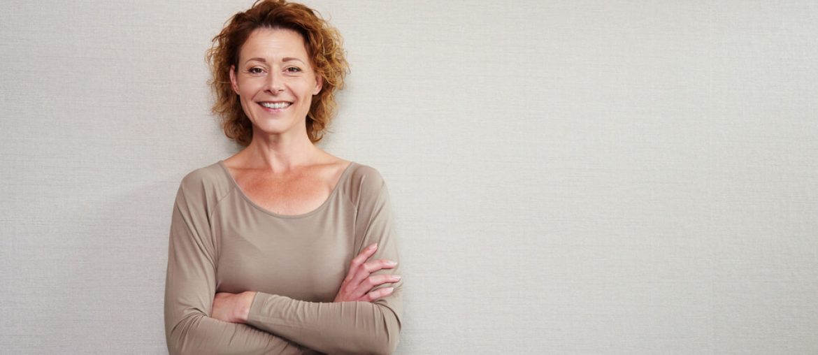 older woman smiling with arms crossed