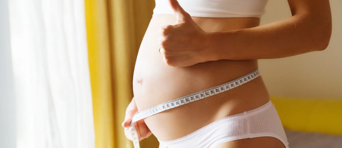 Pregnant woman measuring her belly