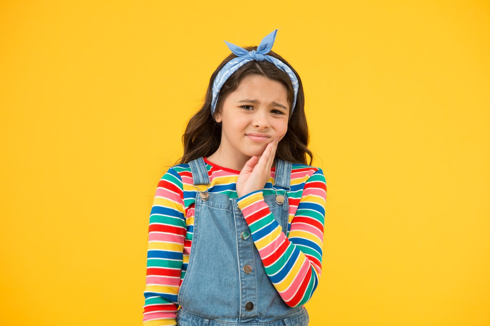 Girl holding her cheek with a swollen tooth