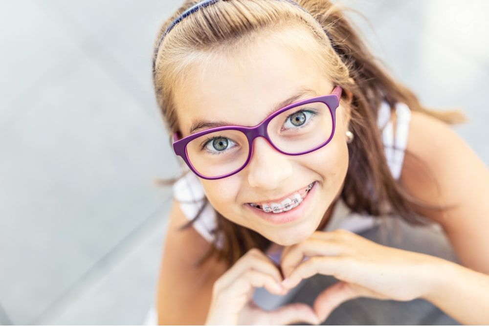 Young preteen girl in glasses wearing braces smiles