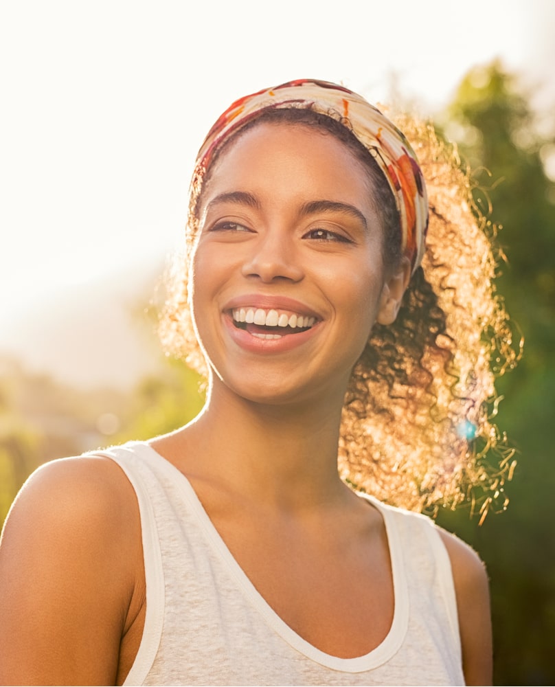 beautiful woman smiling and looking away at park during sunset