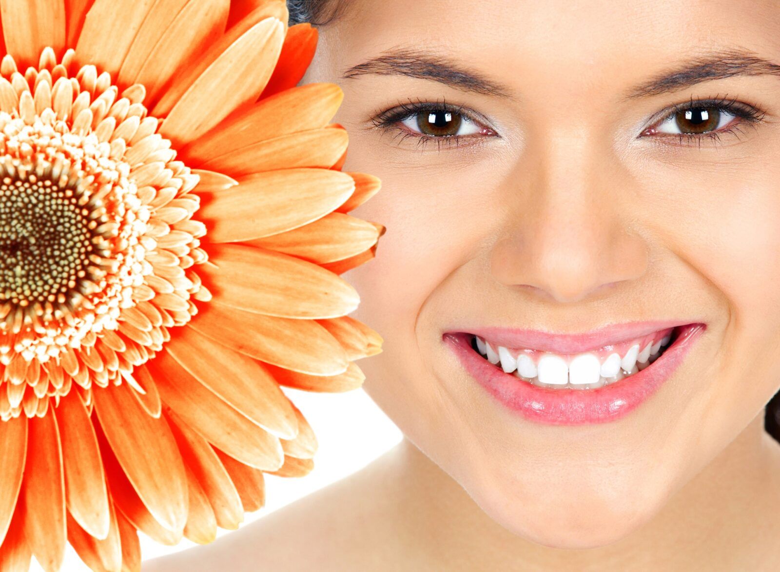 pretty woman smiling beside orange flower. cosmetic dentistry concept