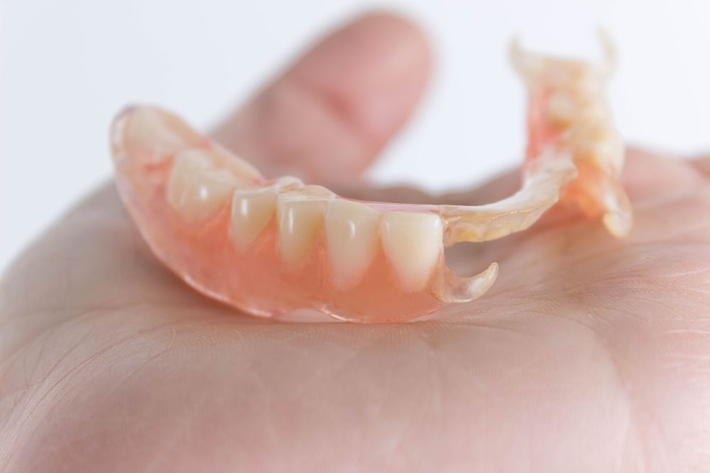 A person holding Partial Dentures in their hand