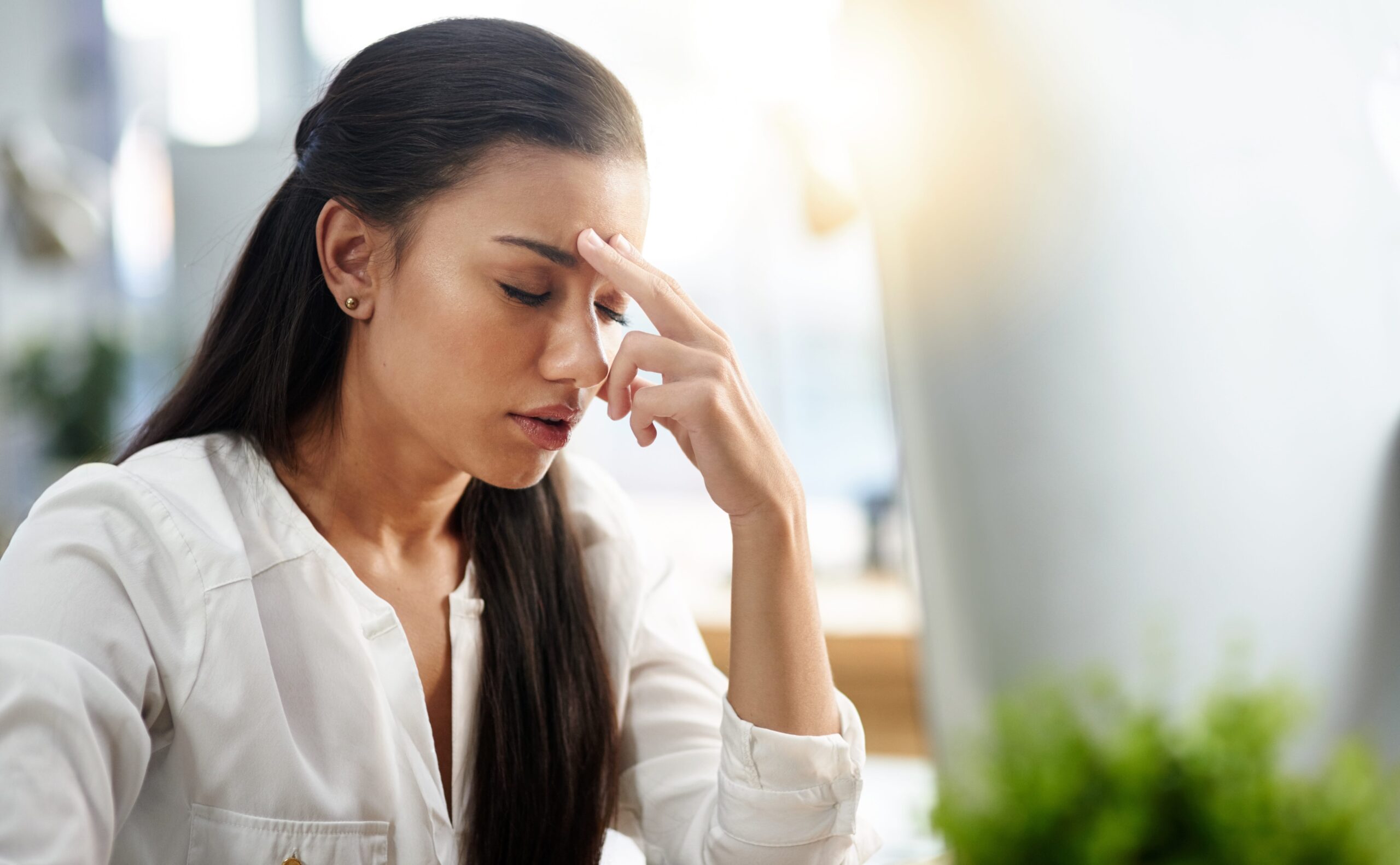 woman at her desk with headache and bright light