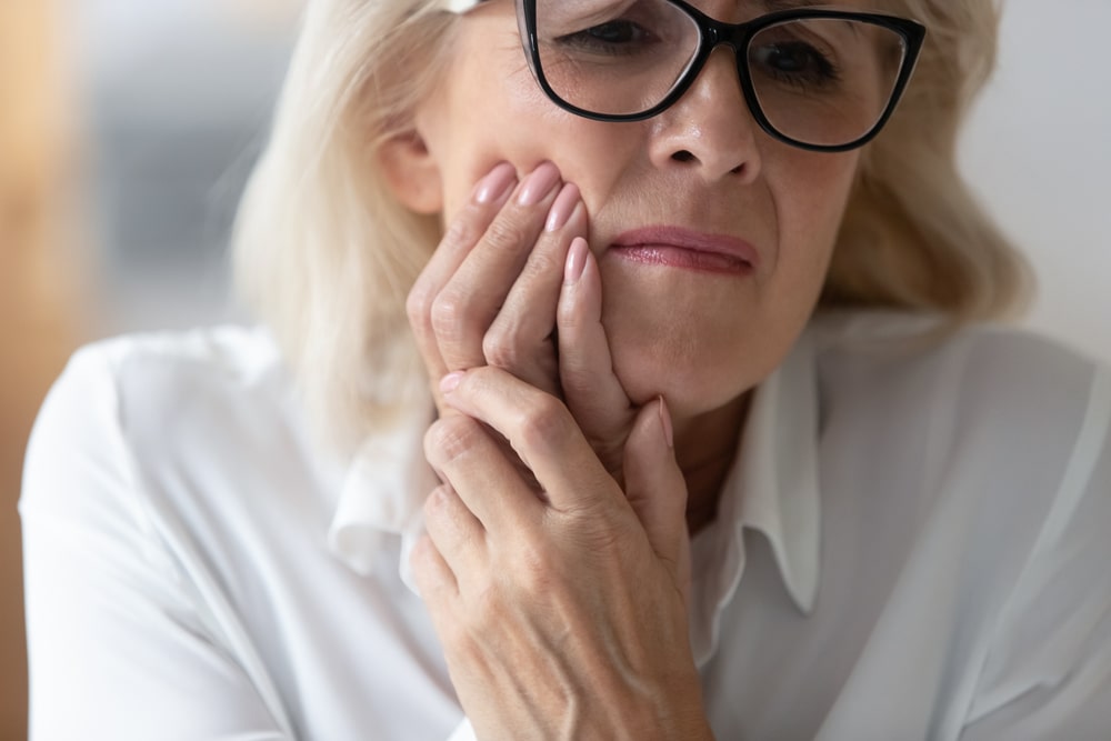 older woman holding her mouth because she has a toothache
