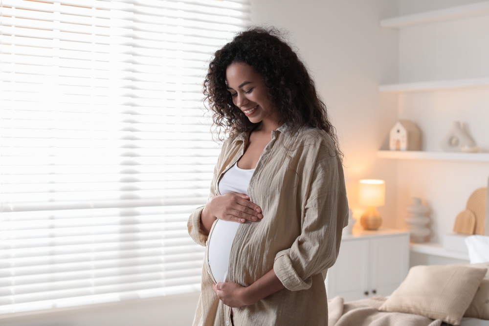 Portrait of beautiful pregnant woman near window at home